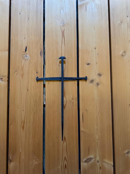 A cross on a wooden door

Description automatically generated