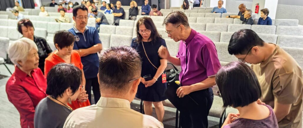 lutheran church in singapore hosts day of prayer in july 2026, with speaker bishop anthony loh praying with a group